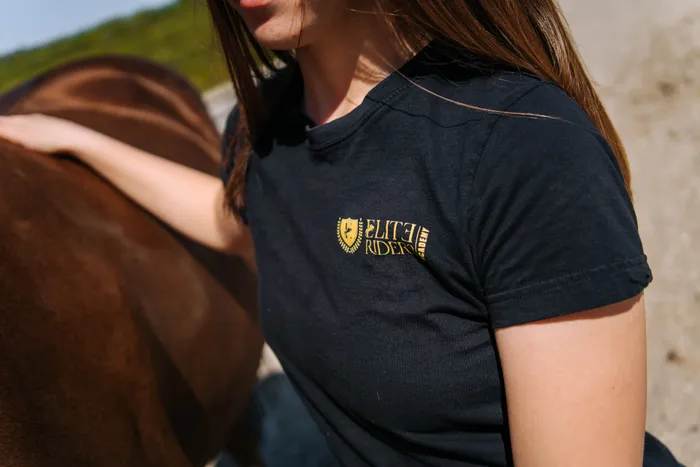 Detaliu cu tricoul echipei Elite Riders Academy, purtat în timpul îngrijirii calului
