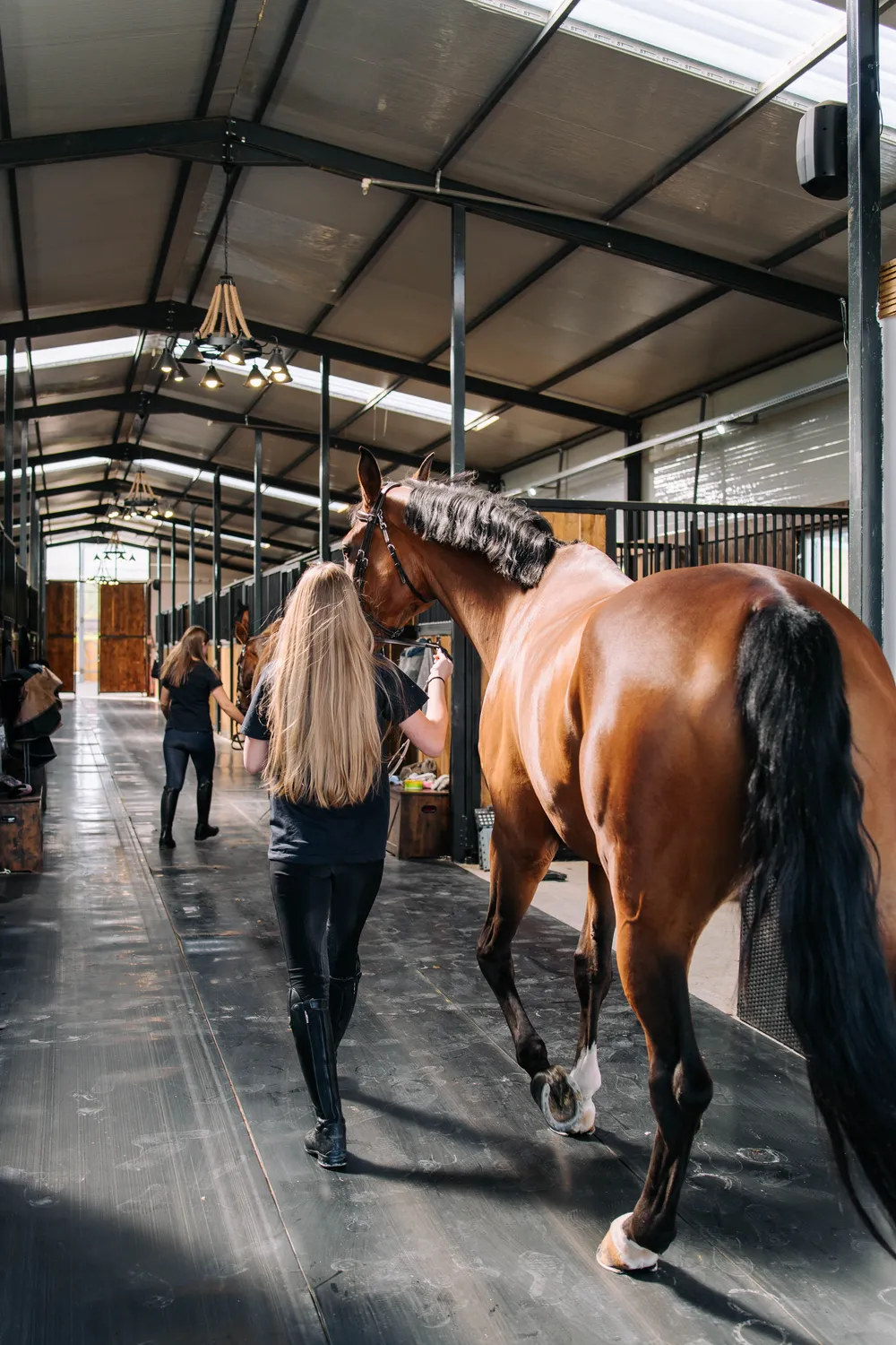 Îngrijitoare alături de cai pe holul grajdului Elite Riders Academy