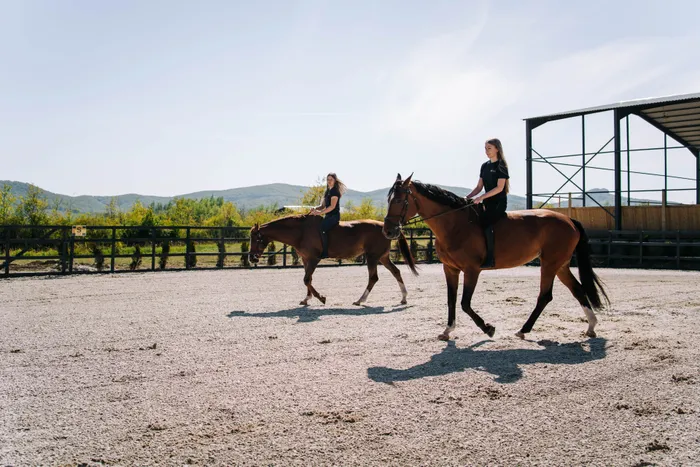 Călăreață în trap pe lângă manejul acoperit al Elite Riders Academy